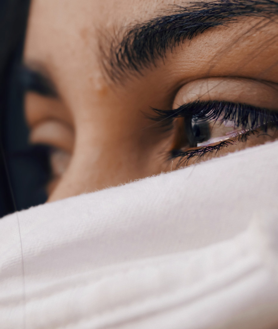 Close-up of a woman’s eye above a white blanket pulled up to her face